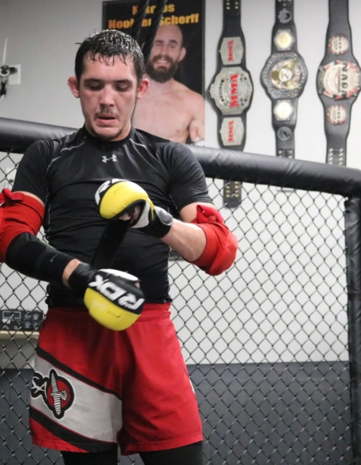 Ethan Riley adjusting his gloves during training inside the Club MMA cage