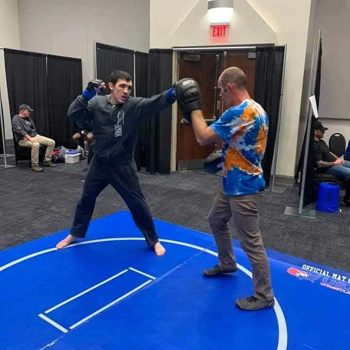 Ethan Riley working punches with a coach holding focus mitts before a fight